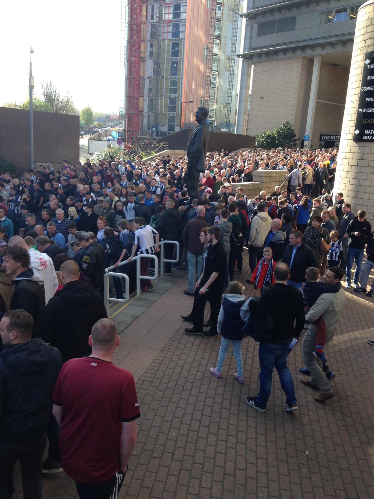 Het Sir Bobby Robson-standbeeld bij St James' Park met Newcastle-fans op matchday