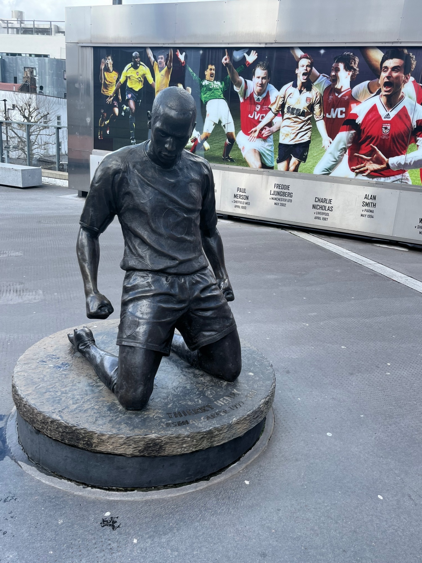 Het Thierry Henry standbeeld voor het Emirates Stadium met daarachter de Arsenal Legends muurschildering
