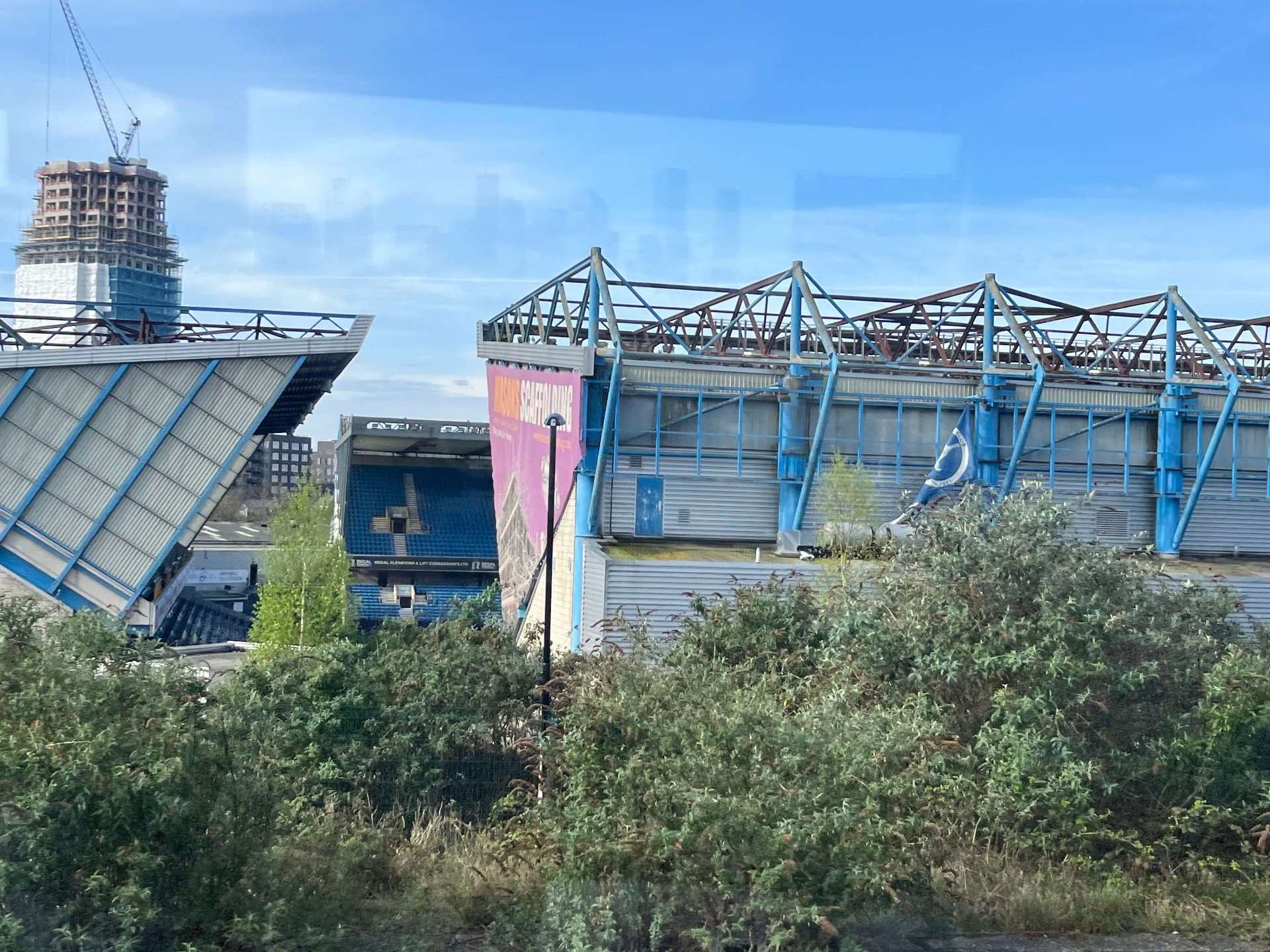 Zijaanzicht van The Den met de karakteristieke blauwe daken en Masons Scaffolding banner