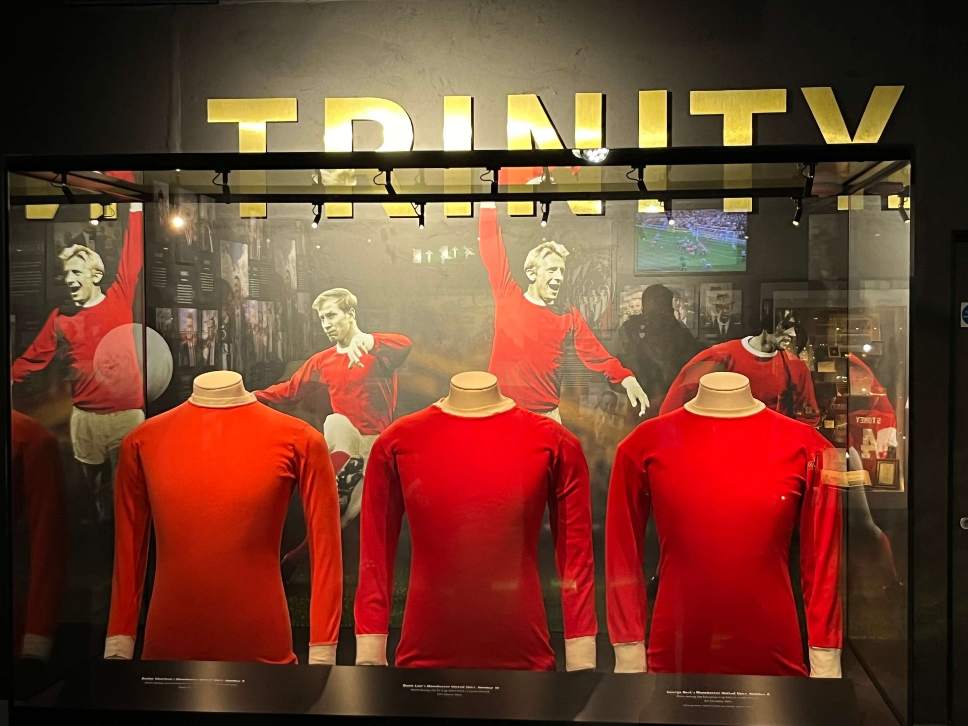 Trinity-vitrine met de shirts van Best, Law en Charlton in het Manchester United museum