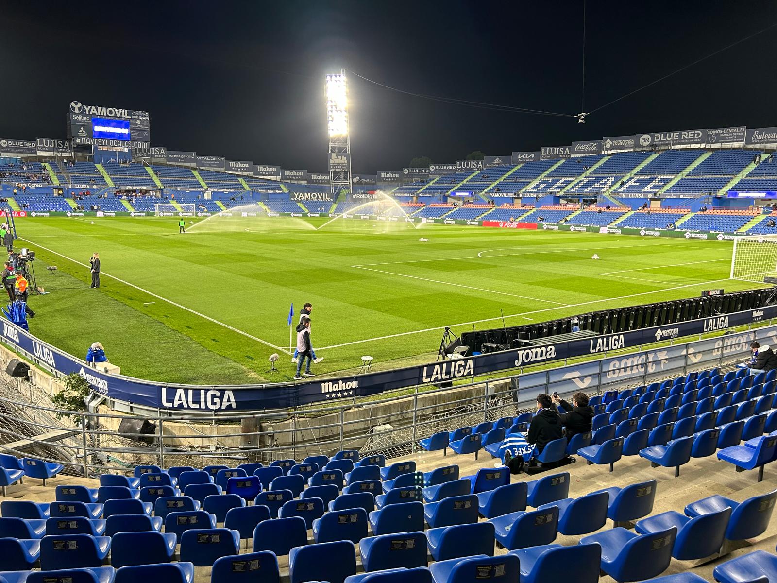 Het Coliseum vlak voor de wedstrijd, met sprinklers op het veld en het Getafe FC logo op de tribune